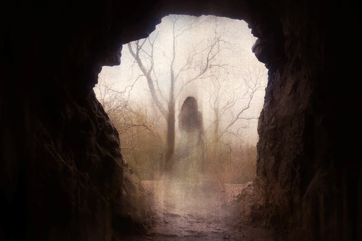 Ghostly woman standing in the entrance of a cave