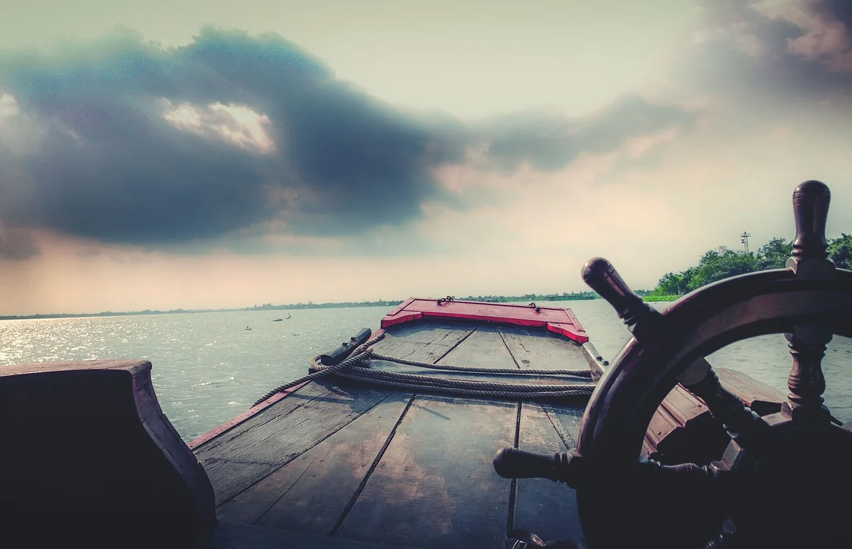 Boat In Mekong River Against Cloudy Sky