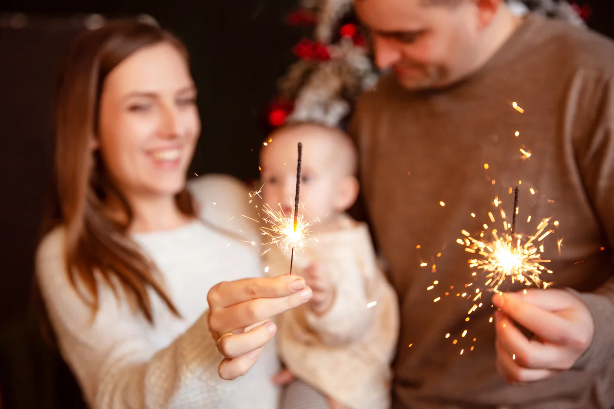 Happy smiling family with newborn baby with sparklers
