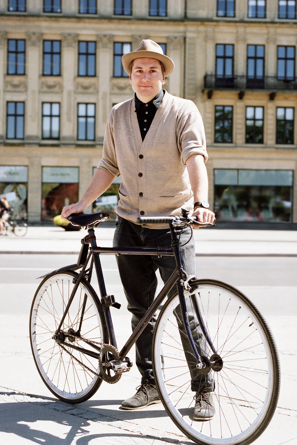 Man on a bicycle wearing slacks and cardigan