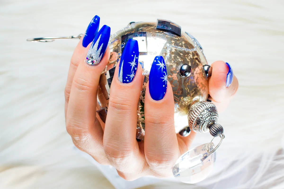 Womans hands with nail art holding a Christmas bauble decoration