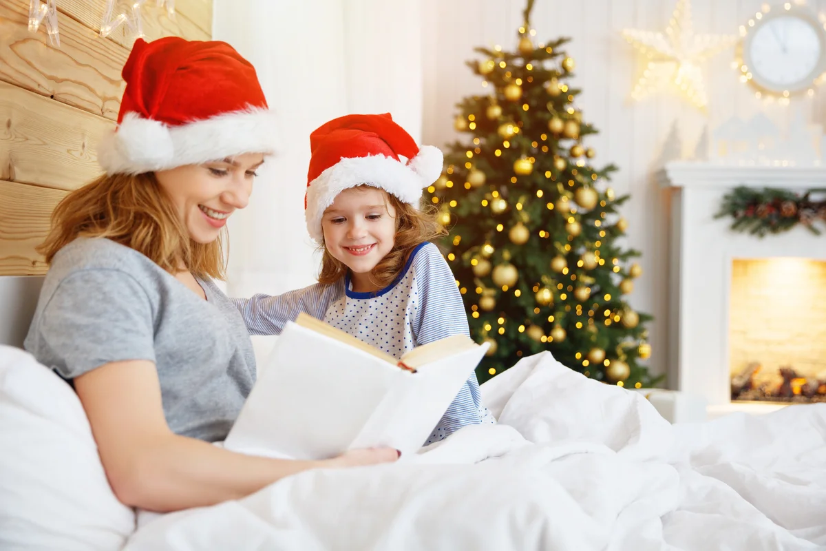 Mother reads book to child in bed at Christmas