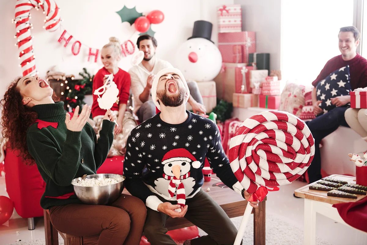Young woman and man catching popcorn in open mouths at christmas party