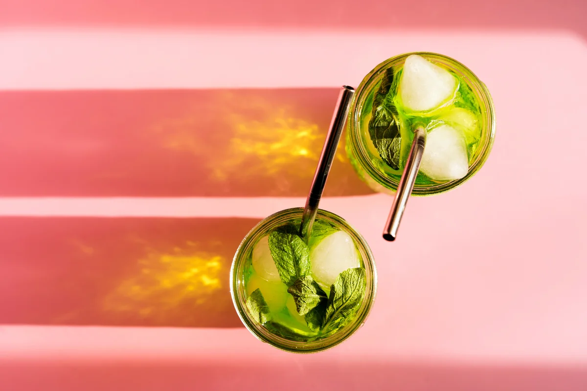 drink with a reusable metal straw on pink sunny background