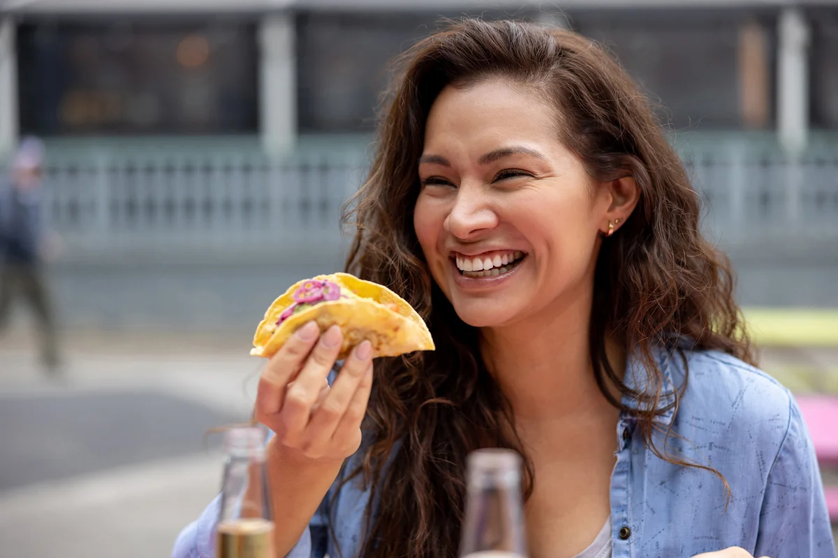 Happy woman eating tacos at a street food restaurant