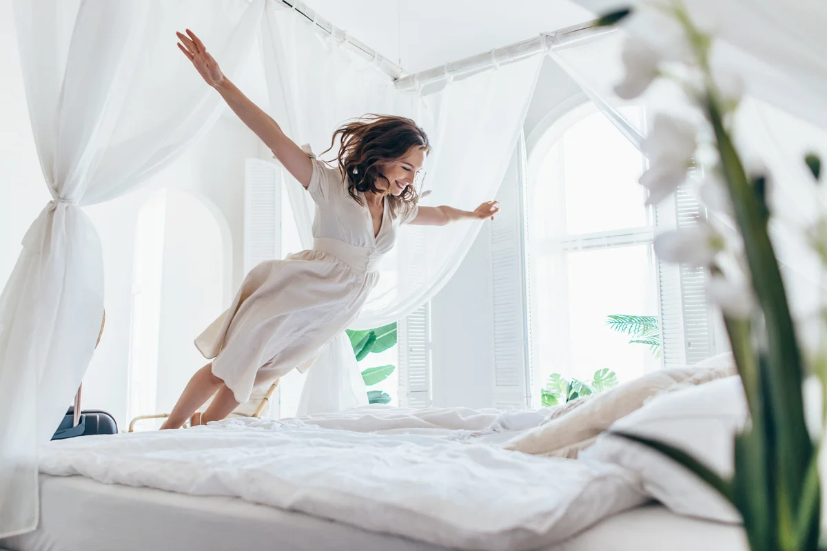Woman jumping on bed