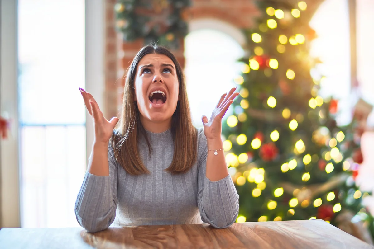 woman sitting at the table at home around christmas tree and decoration crazy and mad
