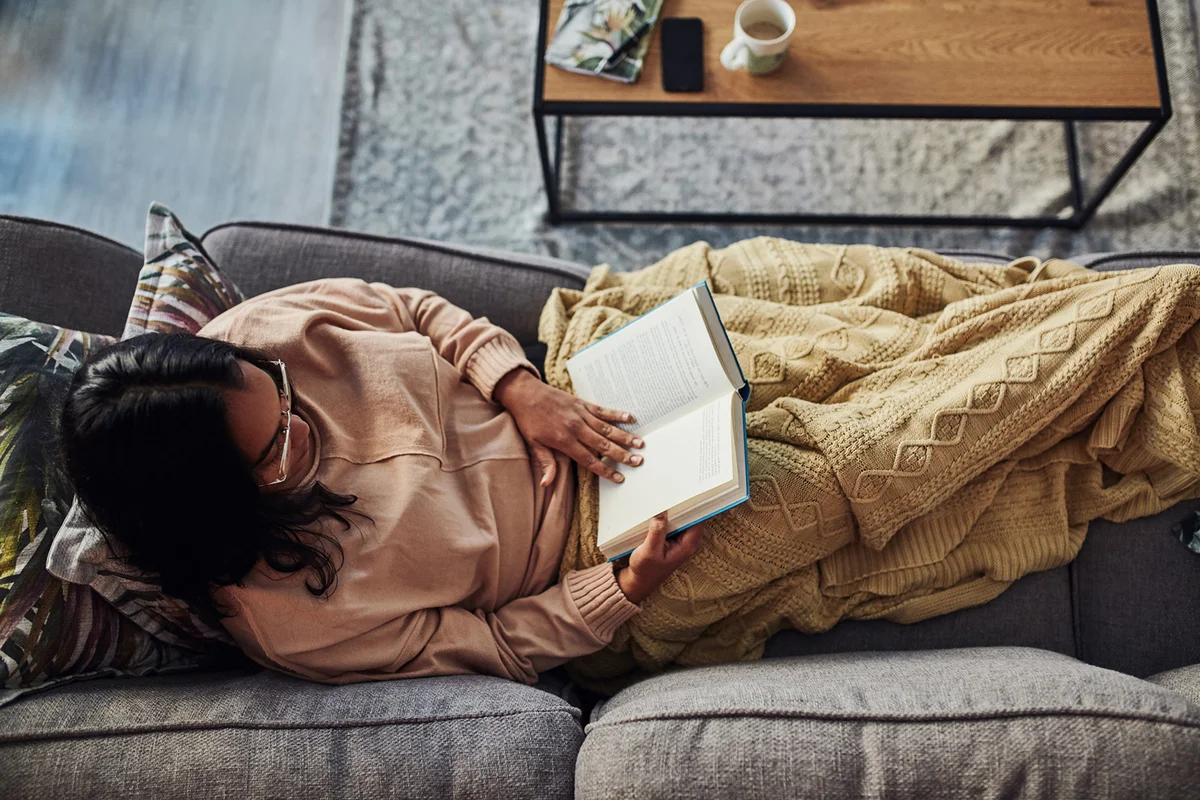 young woman reading a book on the sofa at home