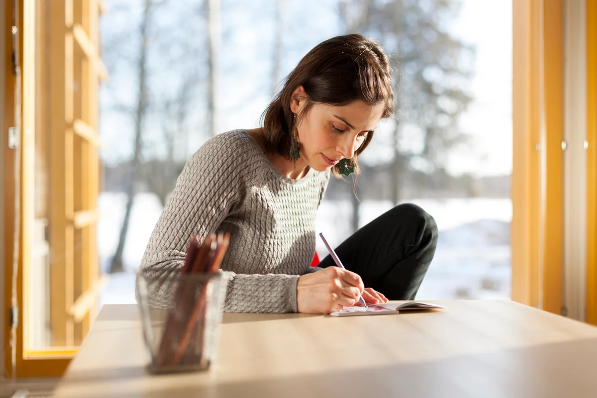 Young woman sitting at table coloring book