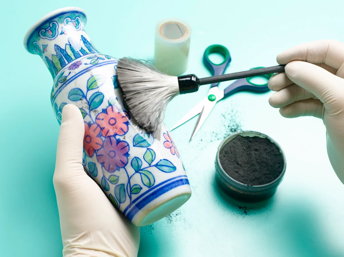 Forensic scientist dusting vase for fingerprints