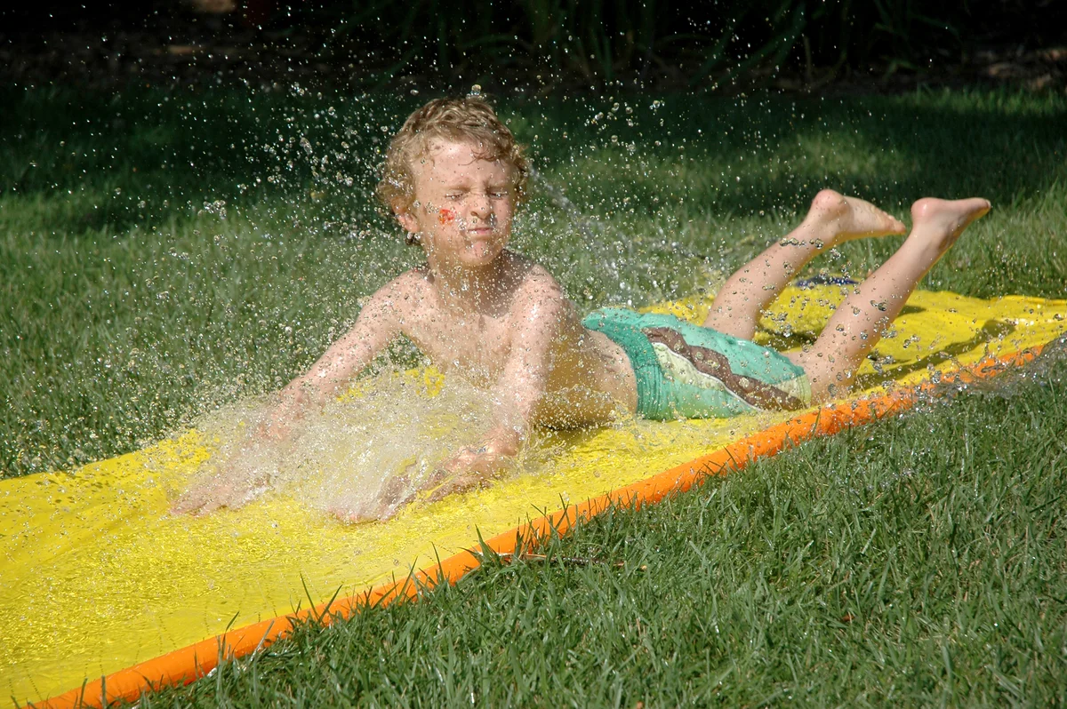 Child plays on a water slide (slip-n-slide)