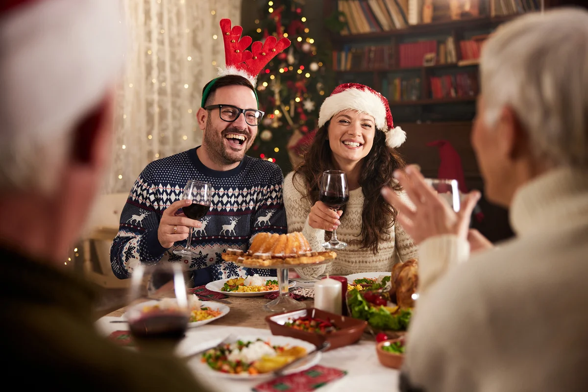 happy couple talking to seniors during Christmas dinner time at home
