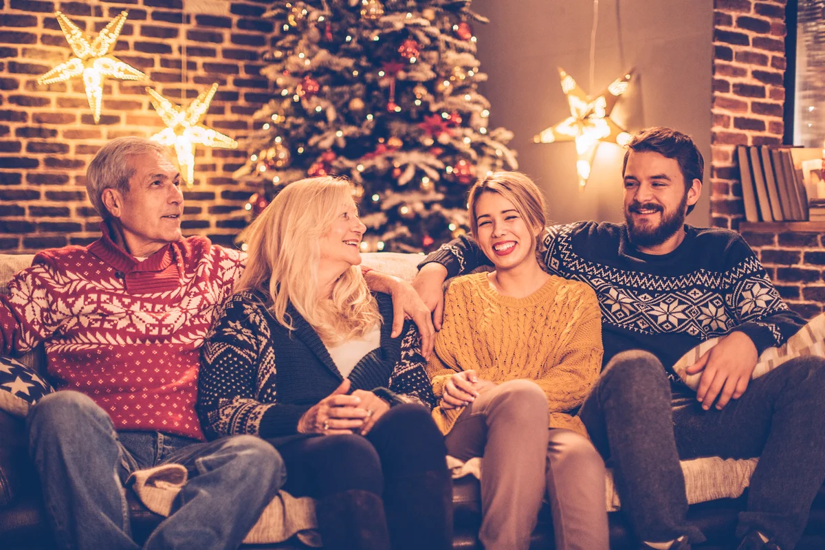 Extended family sitting on sofa with christmas tree