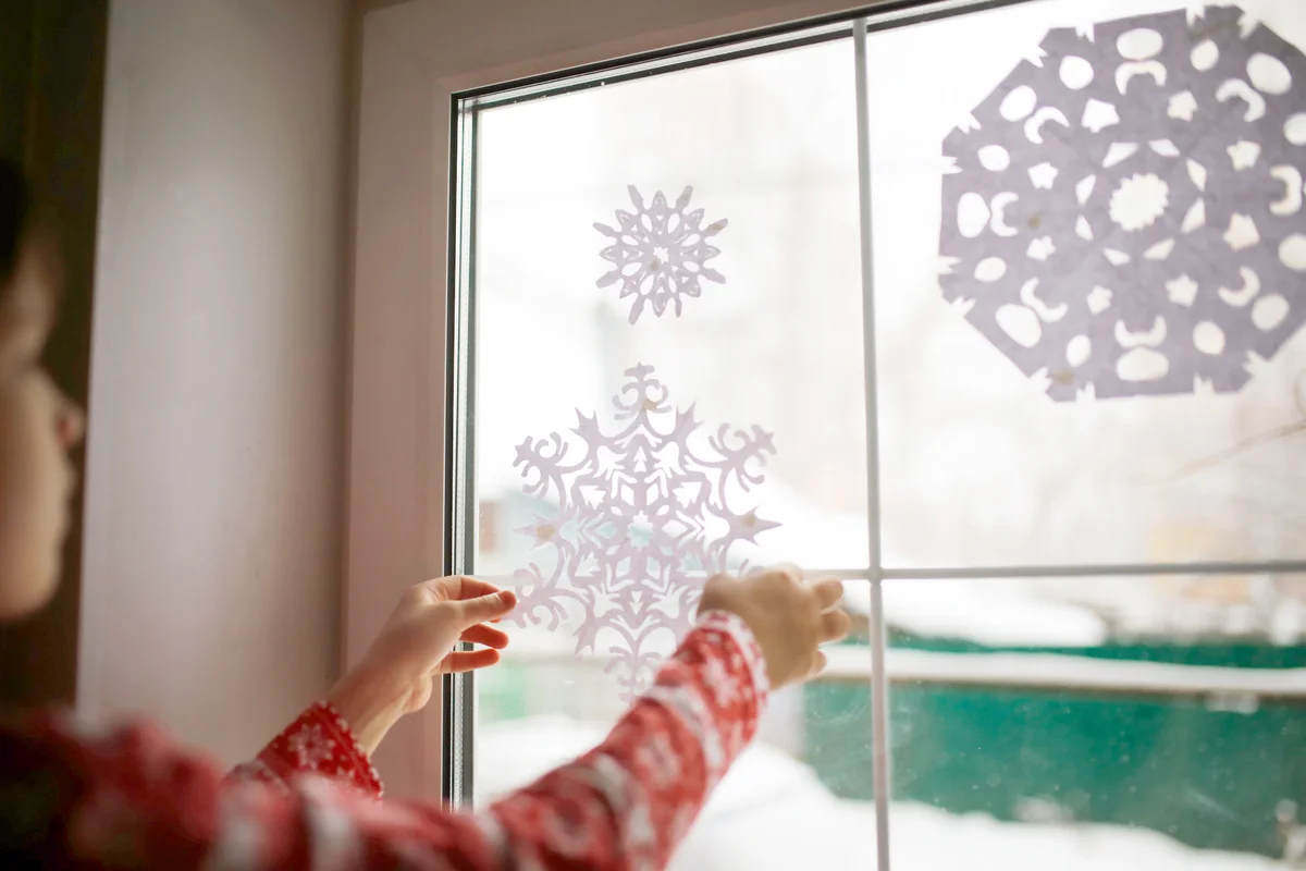 Children adding paper snowflakes to window