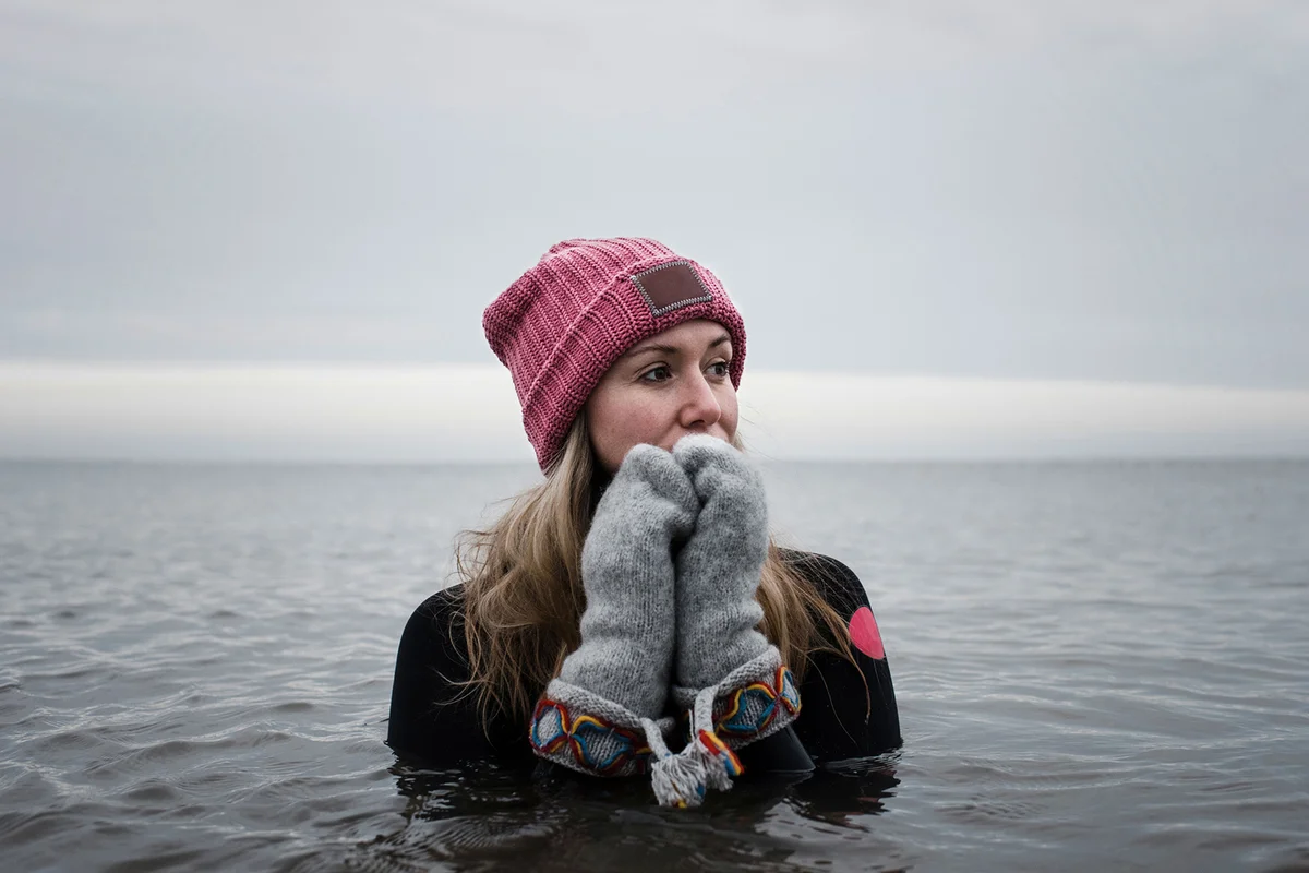 Woman in cold water in the ocean with hat and gloves on