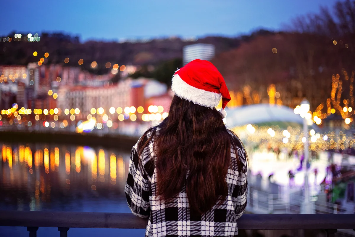 Girl looking at the Christmas lights over the river