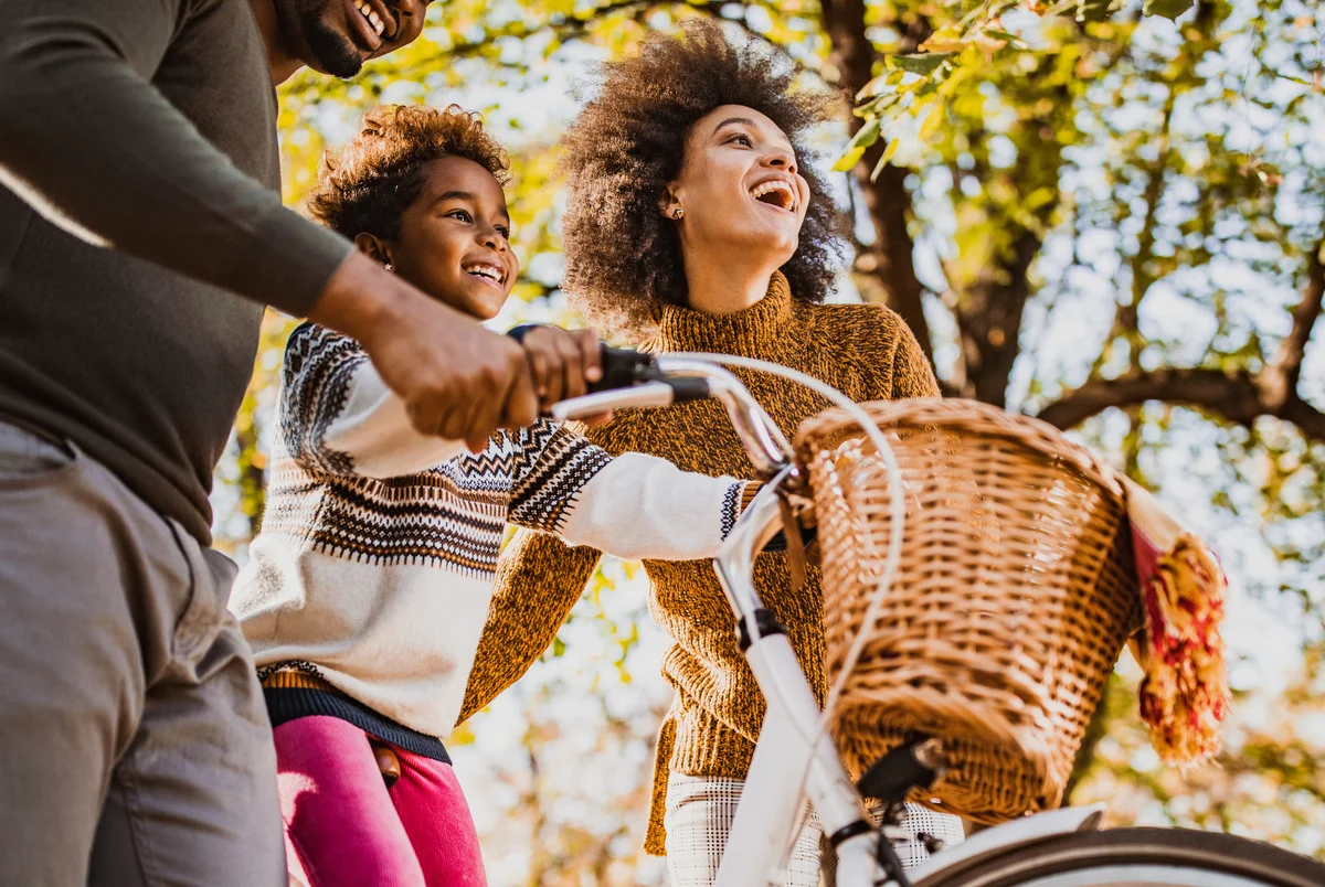 girl on a bike with her parents in nature