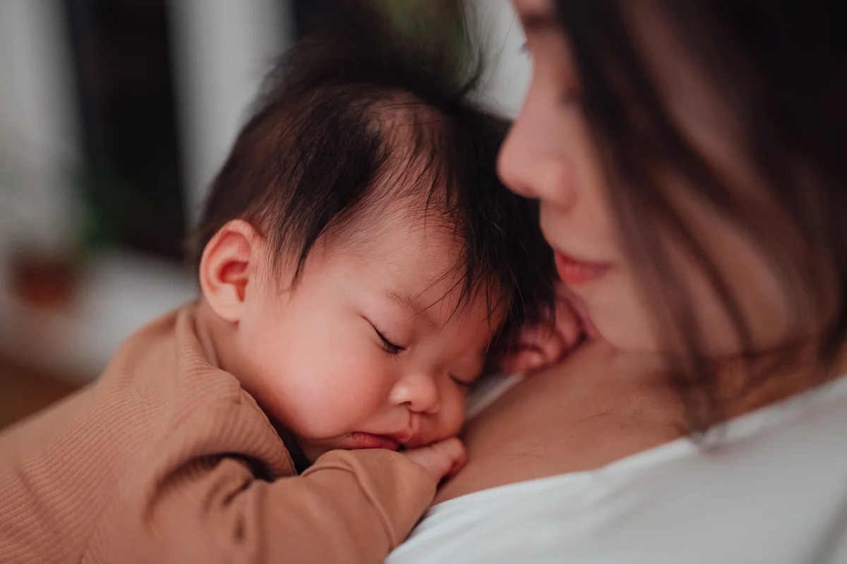 baby girl sleeping peacefully in the arms of her mother
