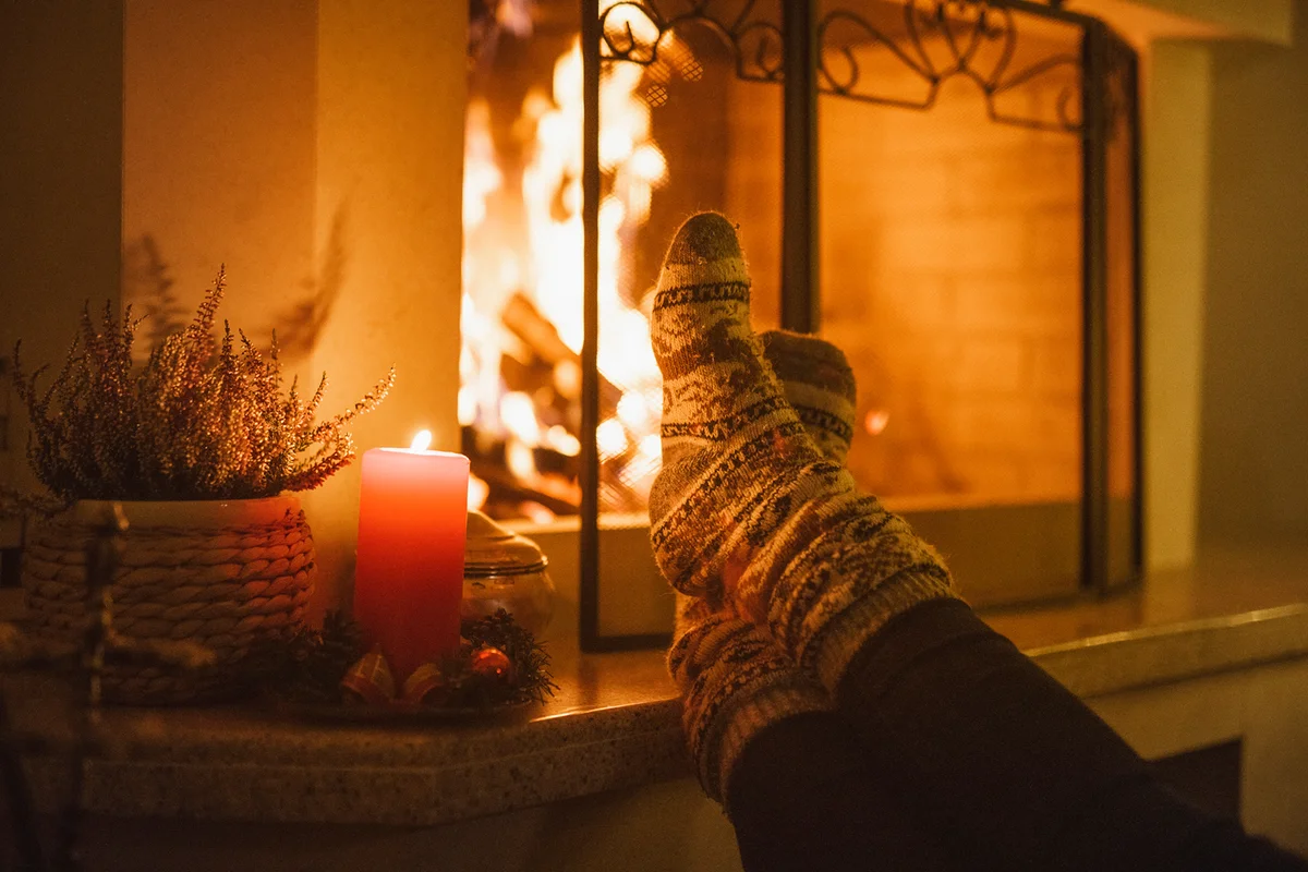 Feet In Christmas Socks Warming On The Fireplace