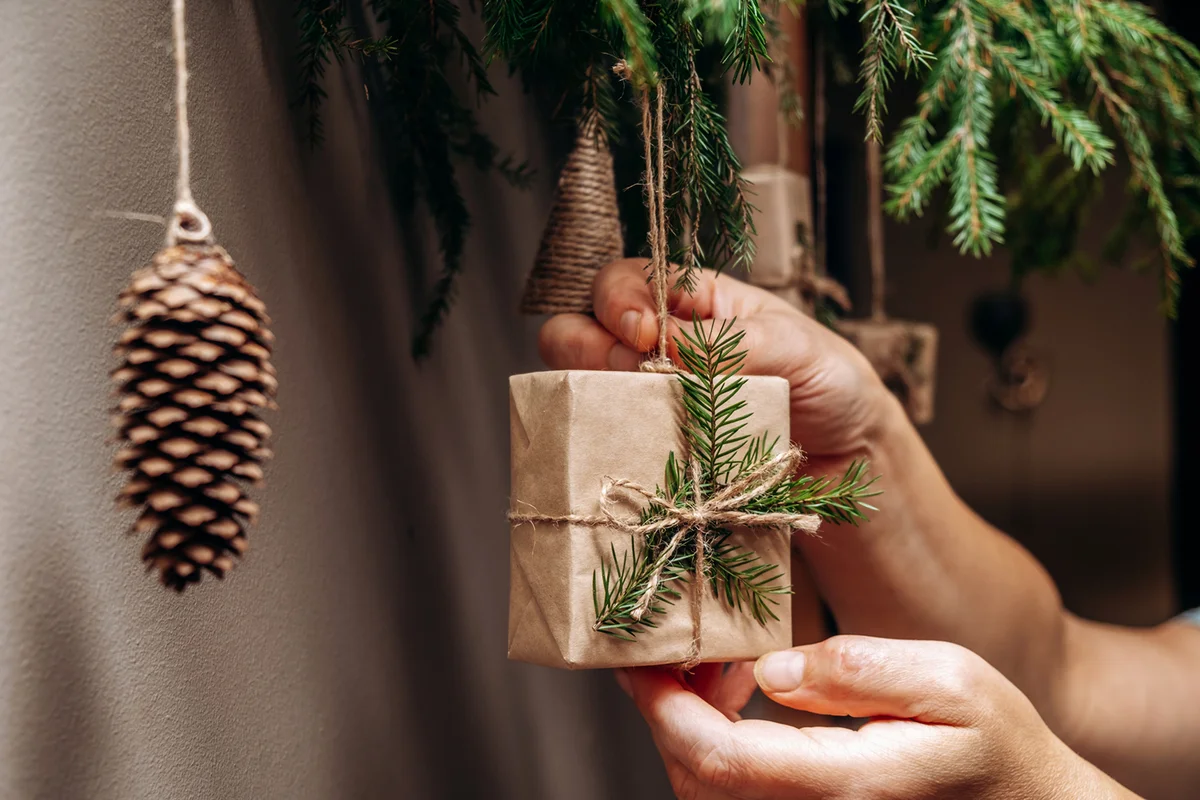 Christmas decor on the wall.Fir branches decorated with gift boxes in craft paper and fir cones