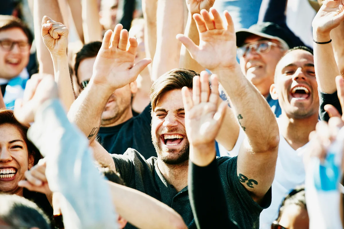 Laughing man cheering with crowd in stadium
