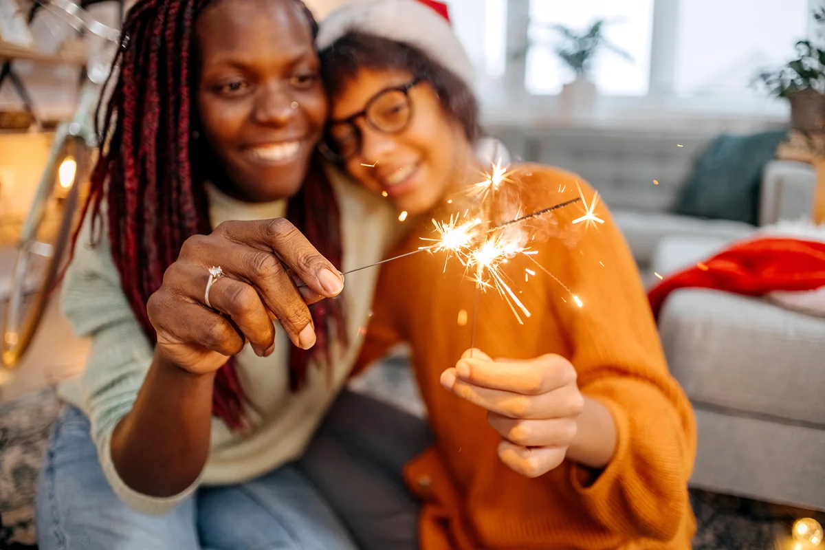 Mother and daughter holding New Year's sparklers at home