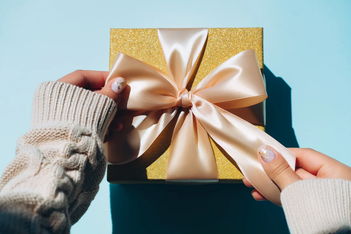 woman adjusting gift box with manicure