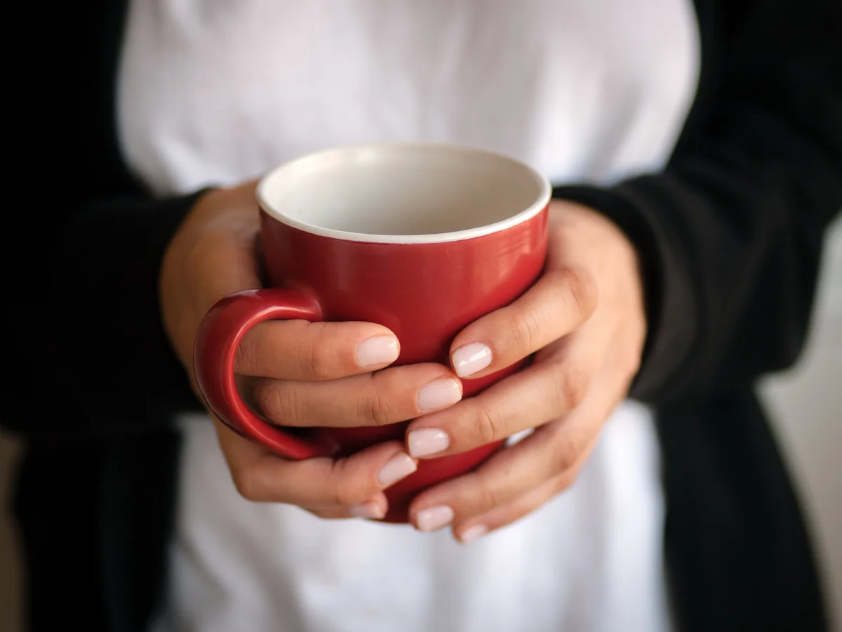 female hands holding a mug of drink