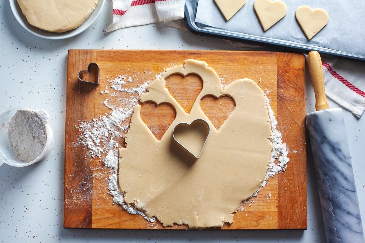 sugar cookie dough rolled and being cut out into hearts
