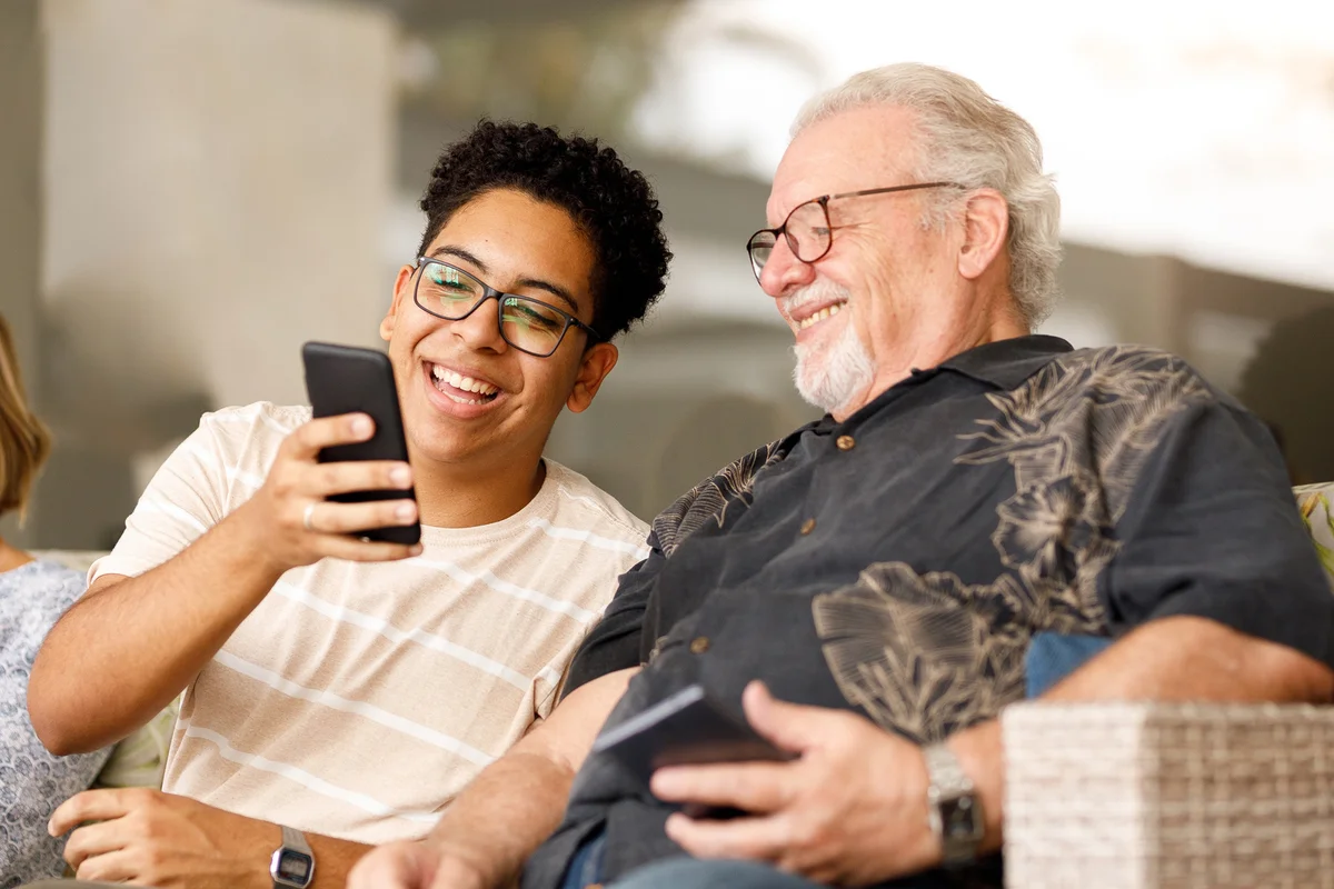 Grandson showing something on cellphone to grandfather