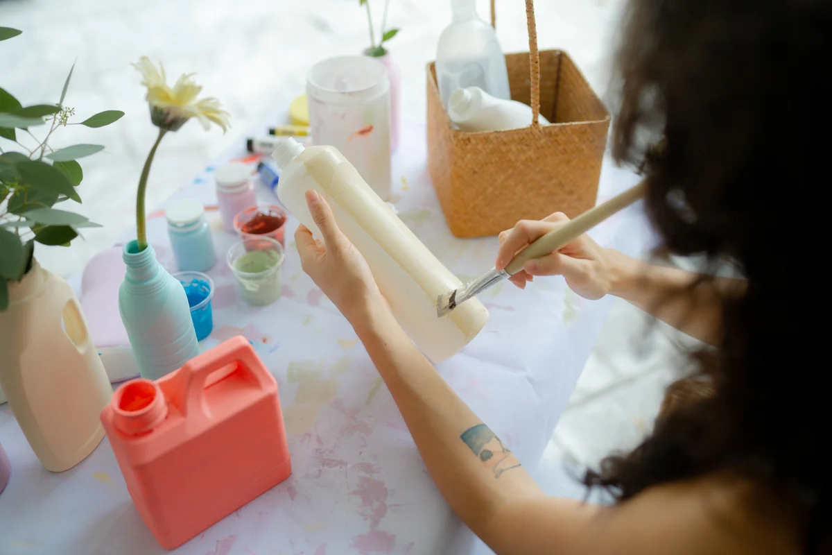 woman painting a plastic bottle