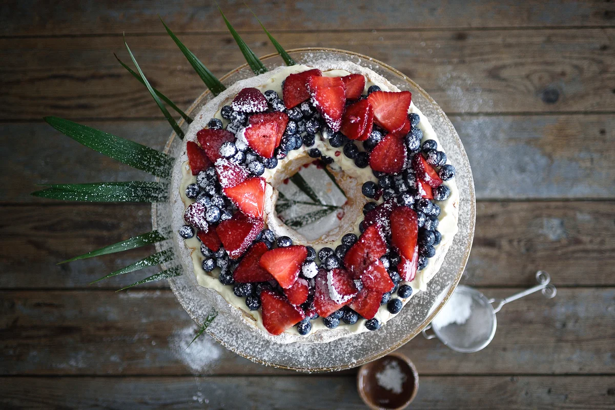 Christmas pavlova wreath with fresh berries on a glass cake stand