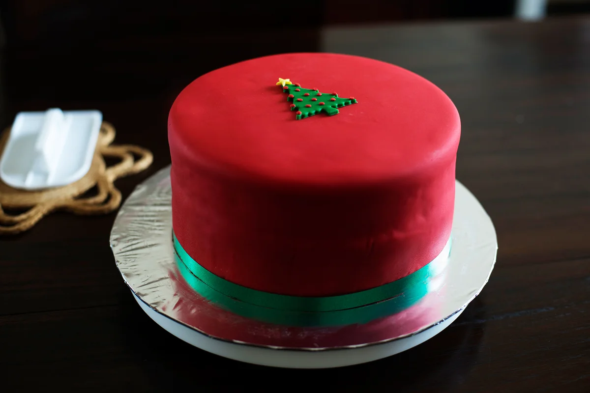 Red fondant covered Christmas cake on wooden table top