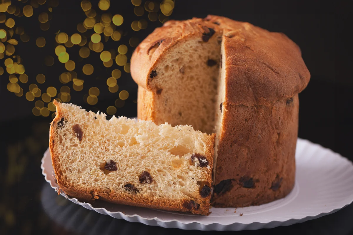 Italian Panettone fruit cake with Christmas lights on the background