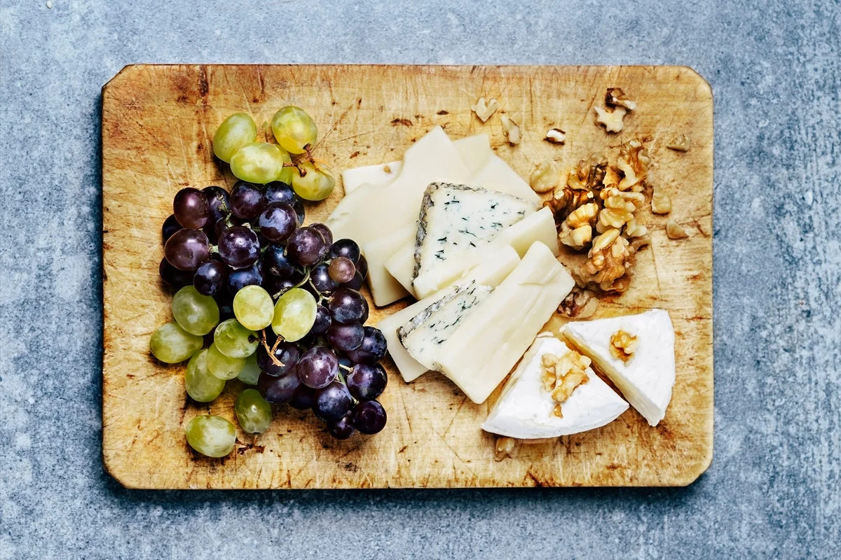 Antipasto (cheese, walnuts, and grapes) on wooden cutting board
