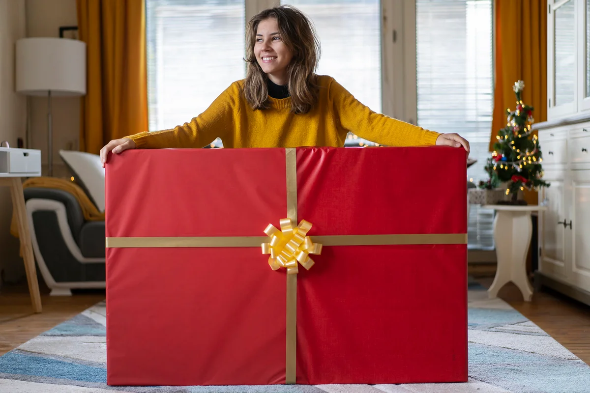 Young girl holding with both hands her huge Christmas gift