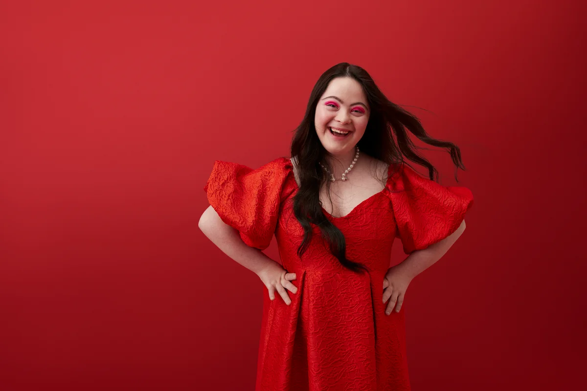Young woman with hand on hip against red background