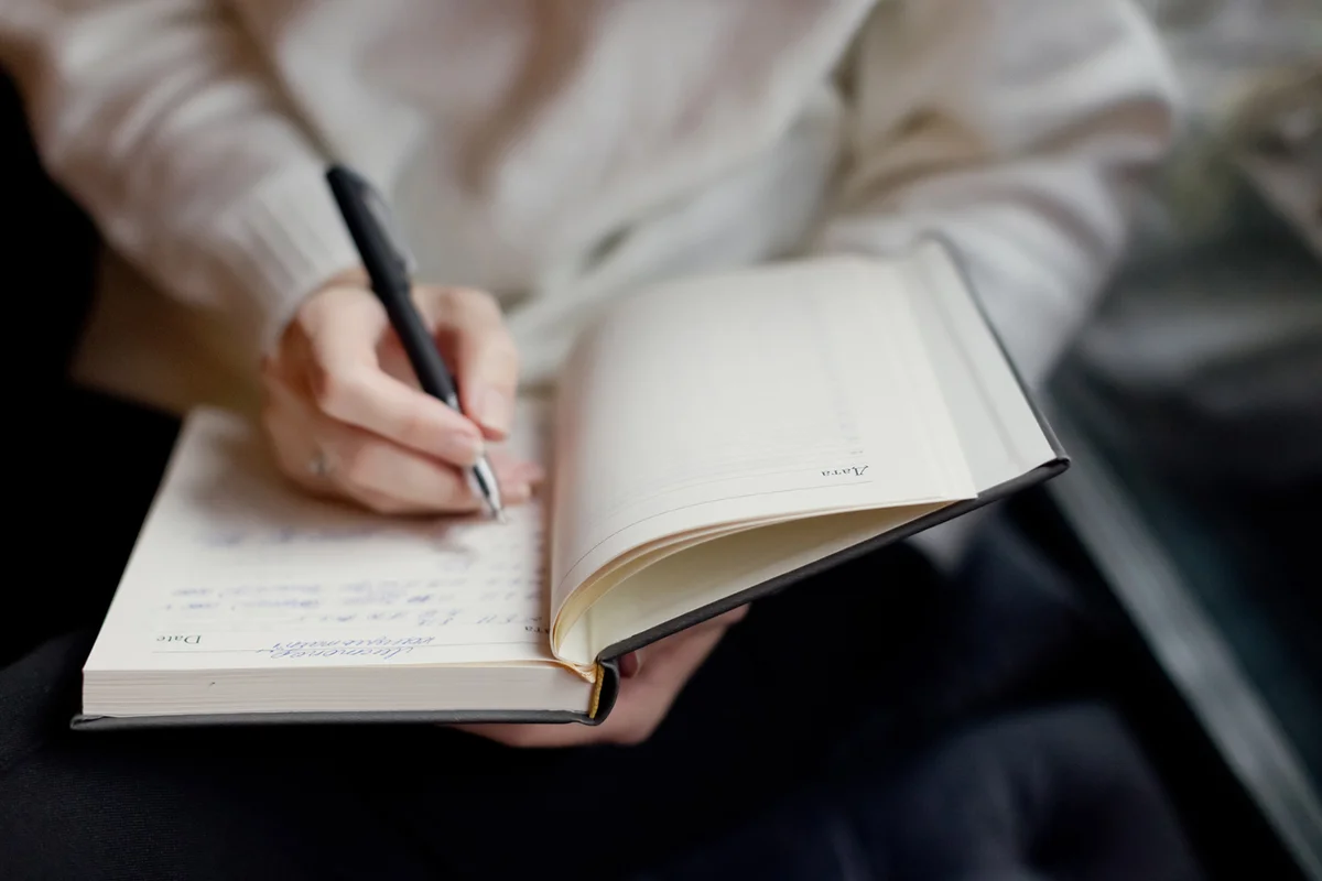 woman writing in notebook indoors