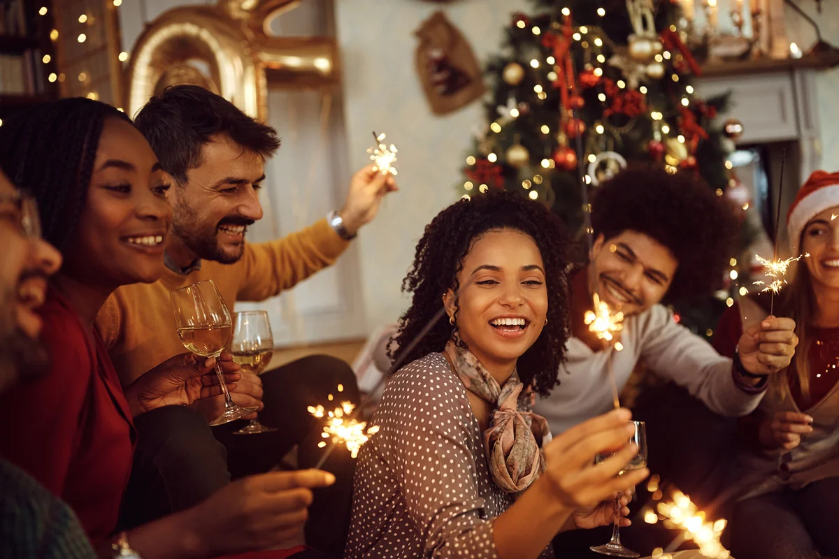 Multiracial group of happy friends using sparklers and having fun on New Year's day at home