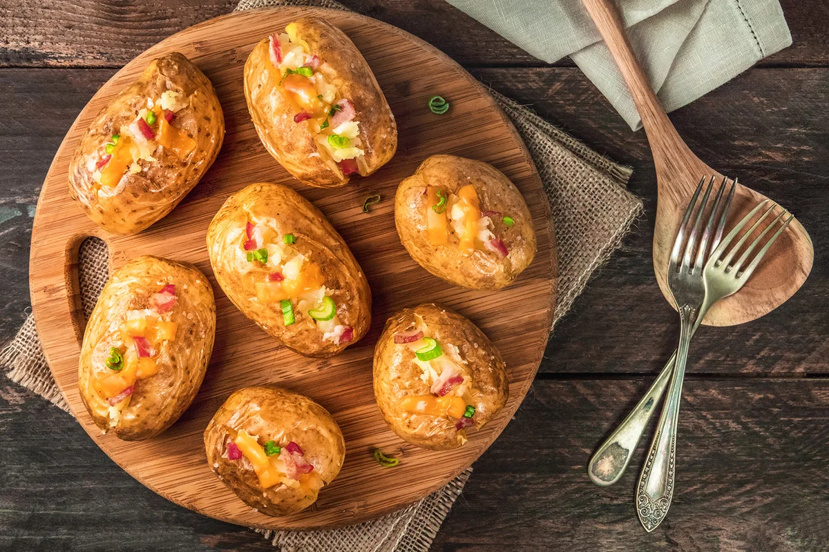 Baked potatoes with cheese, bacon, and two forks -