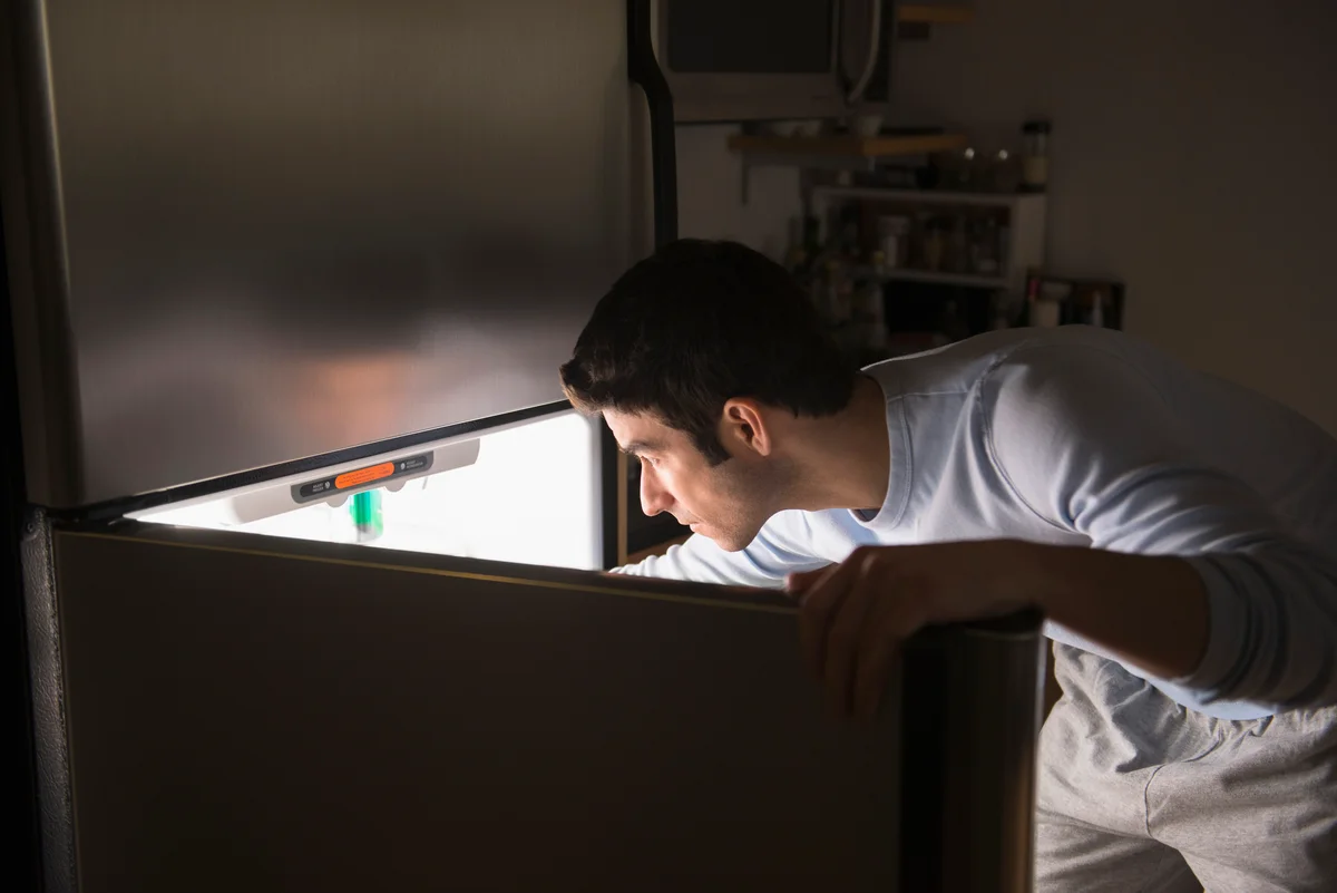 Man opening fridge at night