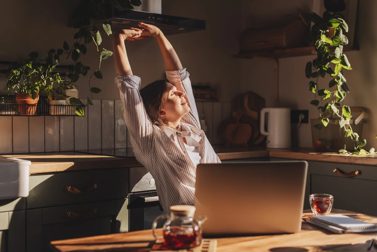relaxed young woman sitting in her kitchen with a laptop