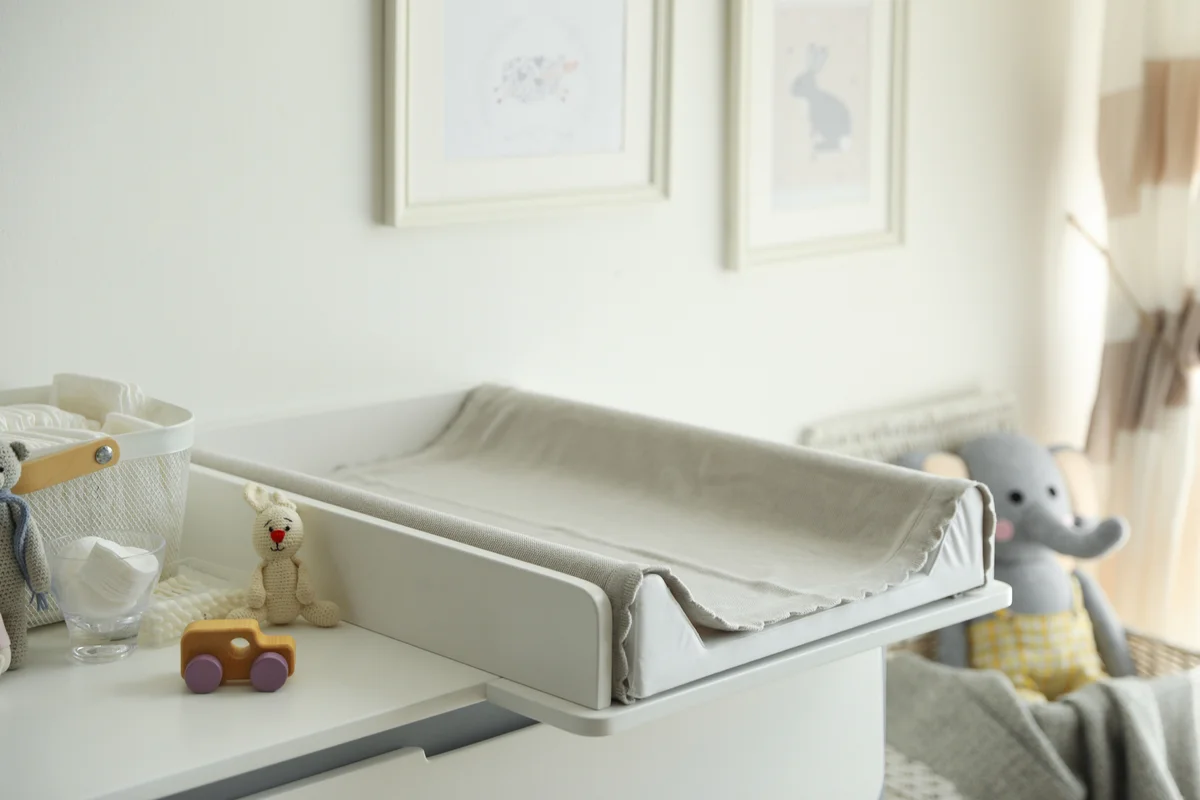 Modern changing table with toys and accessories in baby room