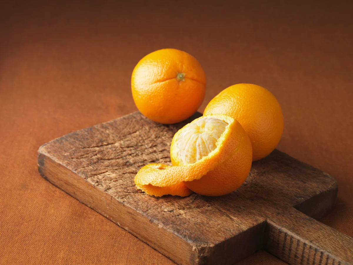 Peeling orange on wooden board