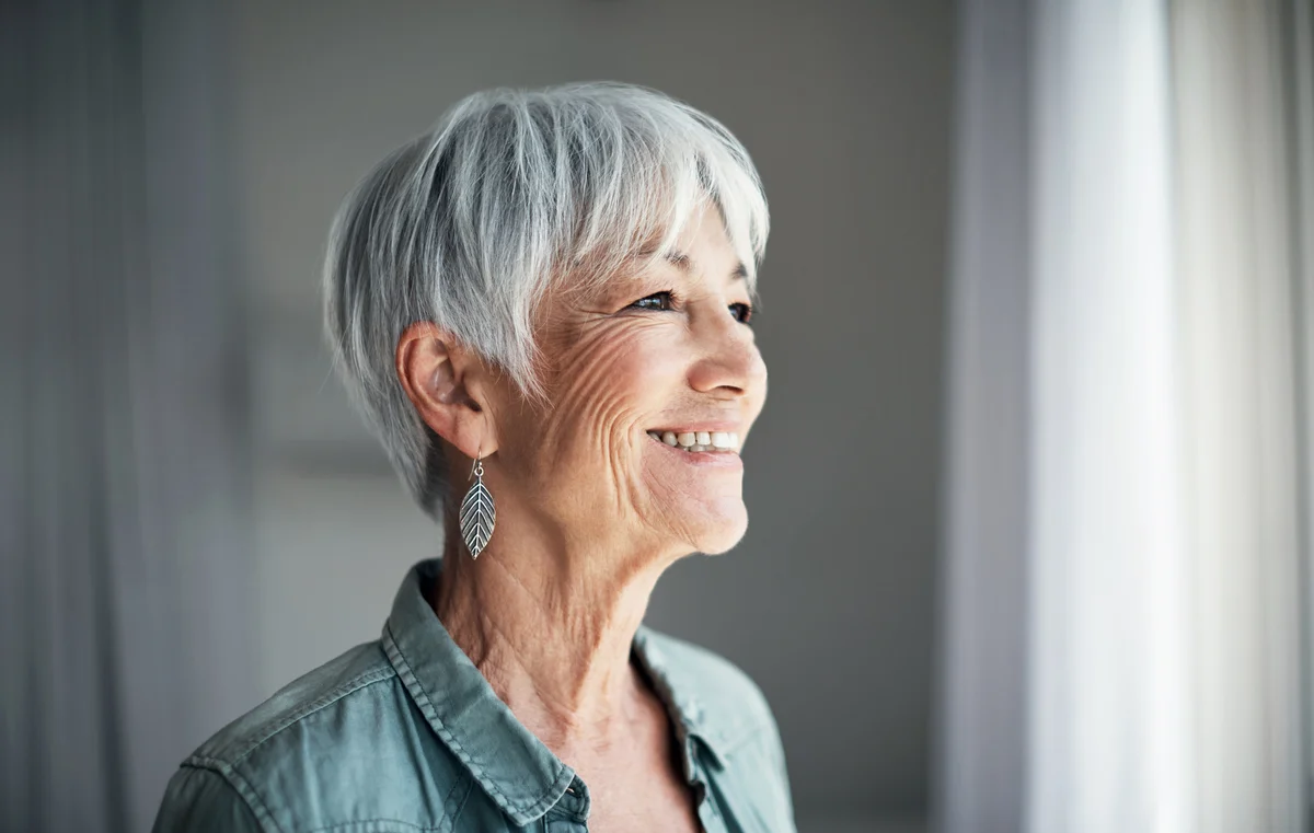 happy elderly woman looking out the window at home