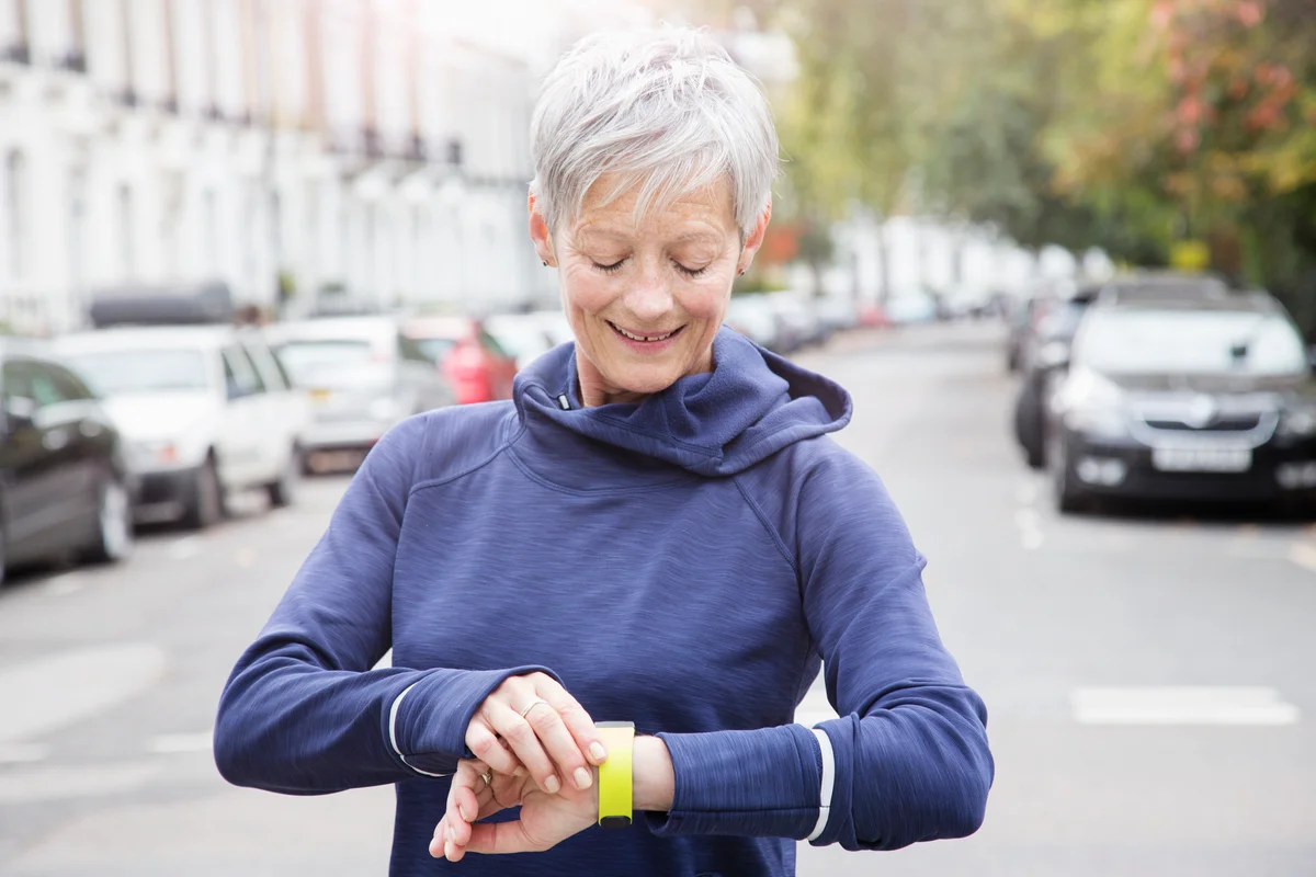 Female senior runner checks activity tracker