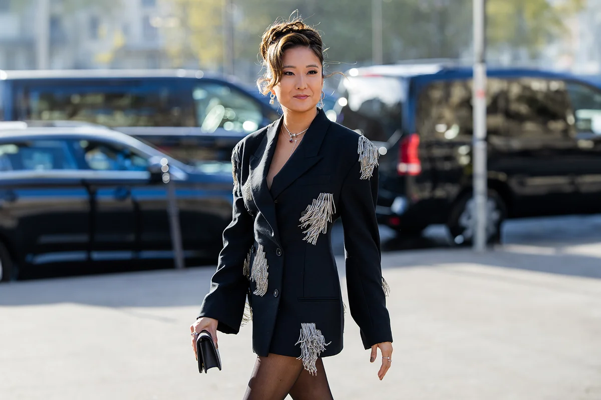 Ashley Park wears black oversized blazer with white fringes
