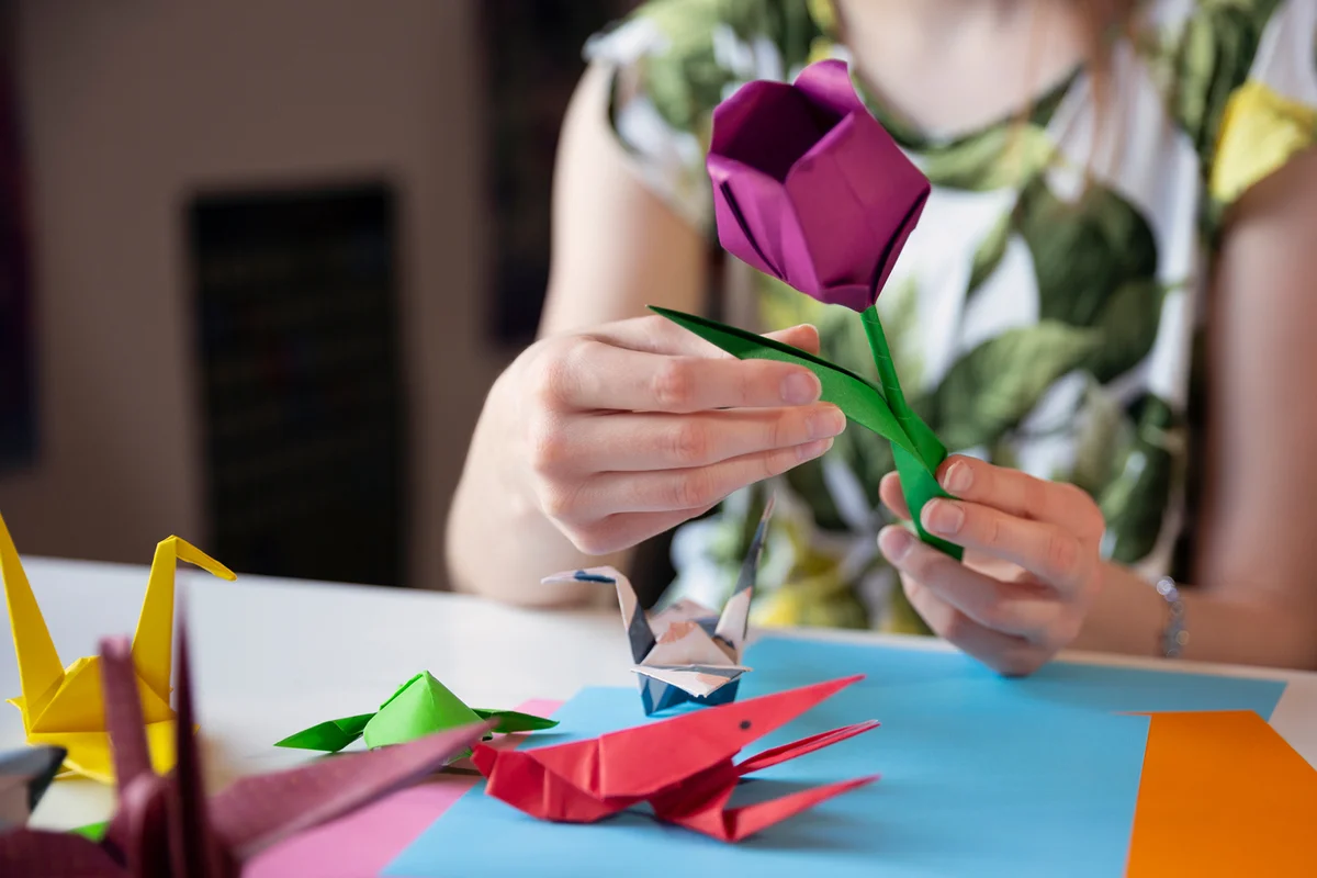 Teenager making origami sculptures with multi-coloured paper