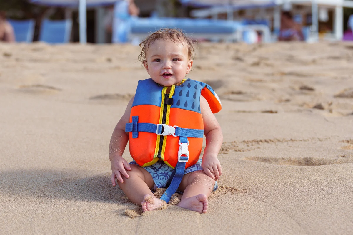 toddler boy wearing life jacket at the beach