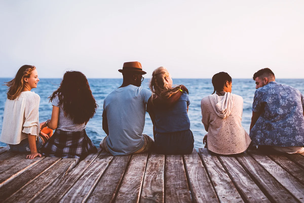 friends sitting on wooden jetty together